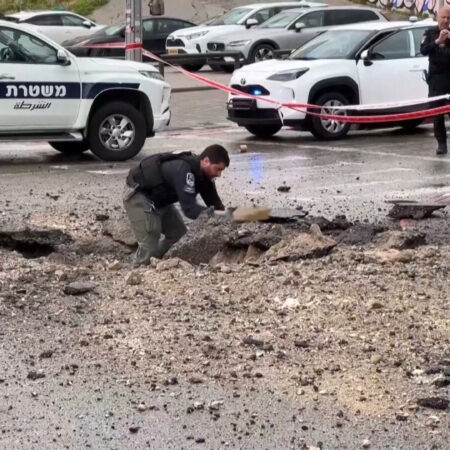 Israeli police inspect damage on the road after missile impact